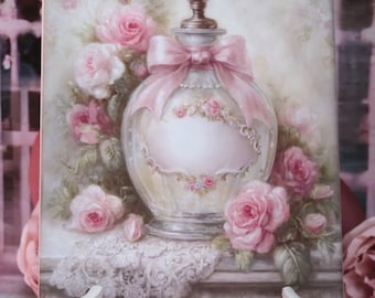Puede incluir: Impresión en lienzo de un frasco de perfume vintage adornado con un lazo rosa y rosas. La obra de arte se exhibe en un caballete blanco. El diseño general evoca una atmósfera romántica y elegante, con tonos rosas y blancos.