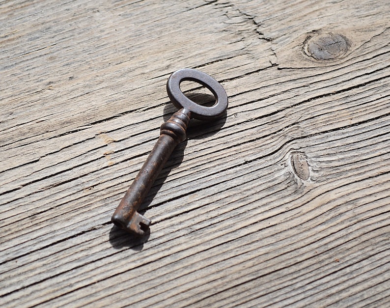 May include: A rusty metal key with a circular keyhole on a weathered wooden surface.
