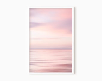 Könnte beinhalten: Ein sanfter, verträumter rosa und lila Sonnenuntergang über einem ruhigen, stillen Gewässer. Der Himmel ist ein Farbverlauf von rosa, lila und weiß mit weichen Wolken. Das Wasser ist hellblau mit ein paar Wellen auf der Oberfläche.