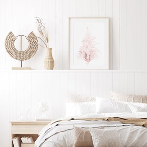 Puede incluir: Un dormitorio blanco con una cama con s&aacute;banas blancas y una manta de color marr&oacute;n. Hay un jarr&oacute;n con flores secas y una pared de cuentas de madera en la repisa sobre la cama. Un estampado enmarcado de un &aacute;rbol rosa est&aacute; en la pared sobre la repisa.