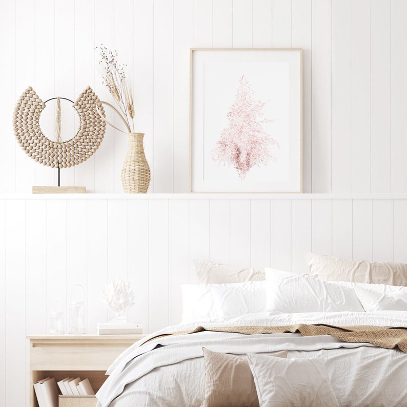 Puede incluir: Un dormitorio blanco con una cama con s&aacute;banas blancas y una manta de color marr&oacute;n. Hay un jarr&oacute;n con flores secas y una pared de cuentas de madera en la repisa sobre la cama. Un estampado enmarcado de un &aacute;rbol rosa est&aacute; en la pared sobre la repisa.