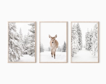 May include: A set of three framed prints featuring a snowy winter forest scene. The center print shows a young deer standing in the snow, while the left and right prints show snow-covered trees.