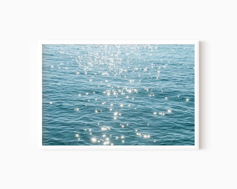 May include: A close-up of sparkling water with the sun reflecting off the surface. The water is a light blue color and the reflections are white.