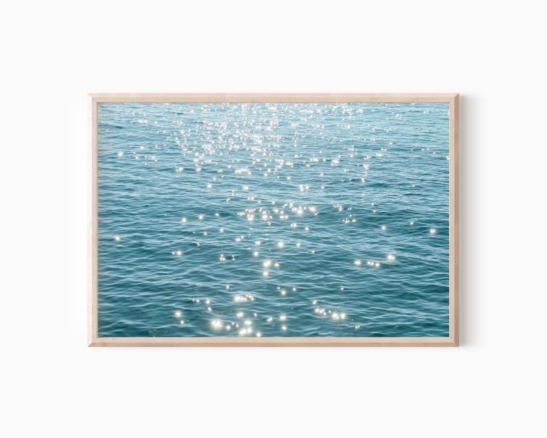 May include: A photograph of a blue body of water with sunlight reflecting off the surface, creating a sparkling effect.