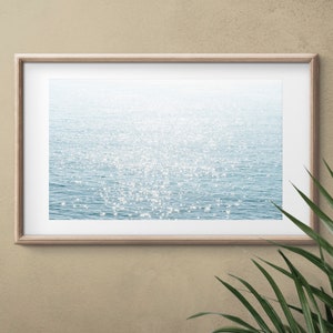 May include: A framed photograph of a sparkling blue ocean with sunlight reflecting off the water.