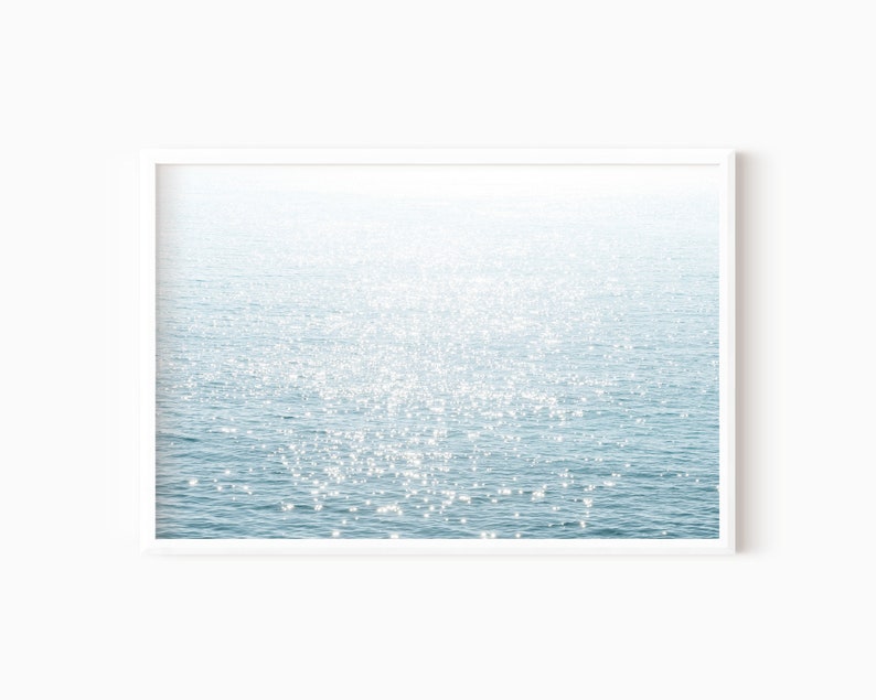 May include: A photograph of a sparkling blue ocean with sunlight reflecting off the water.