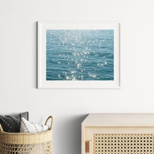 May include: A photograph of sparkling blue water with sunlight reflecting off the surface.