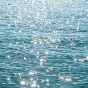May include: A close-up of sparkling blue water with sunlight reflecting off the surface.
