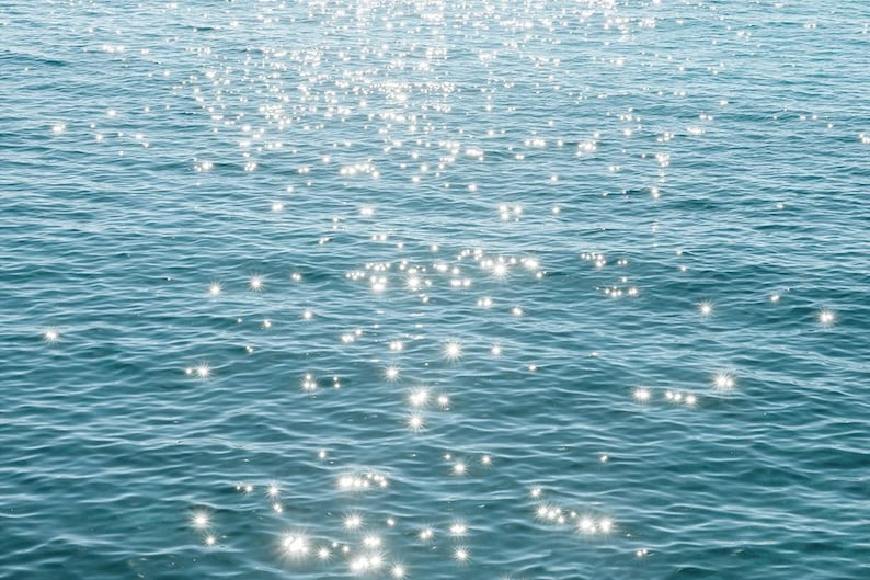 May include: A close-up of sparkling blue water with sunlight reflecting off the surface.