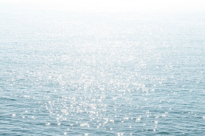 May include: A close-up of a sparkling blue ocean with sunlight reflecting off the water.