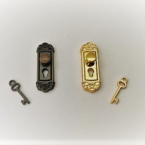 Könnte beinhalten: Zwei Miniatur-Türknäufe mit Schlüsseln. Einer ist golden und der andere ist bronzefarben.