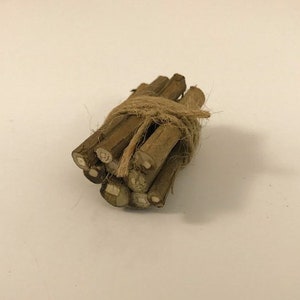 May include: A bundle of small, brown sticks tied together with twine. The sticks are arranged in a neat pile and are ready for use as kindling.