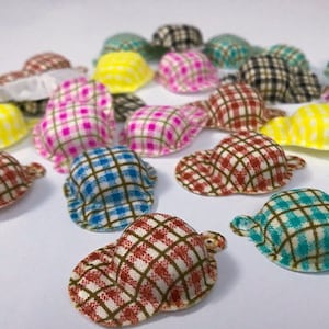 Peut inclure: Une collection de 15 chapeaux miniatures à carreaux de différentes couleurs, dont le jaune, le rose, le bleu, le vert et le marron. Les chapeaux sont en tissu et ont un motif à carreaux.