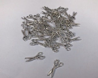 May include: A pile of silver-colored miniature scissors. The scissors are arranged in a random pattern, with some overlapping. The scissors are all the same size and shape.