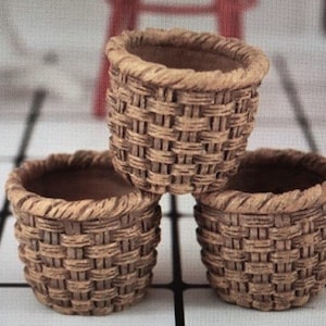 May include: Three brown woven baskets, stacked on top of each other. The baskets are made from a natural material and have a rustic look.