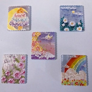 Puede incluir: Cinco azulejos decorativos pequeños, cuadrados, con escenas pintadas. Los azulejos presentan un arcoíris, un hongo, flores, una escena de montaña y un cielo con nubes.