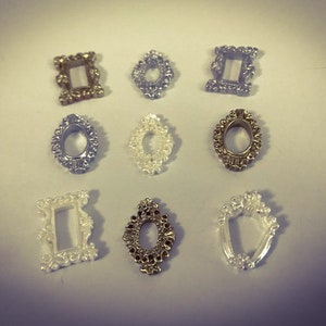 May include: Nine decorative metal picture frames in various shapes and sizes. The frames are silver, gold, and white.