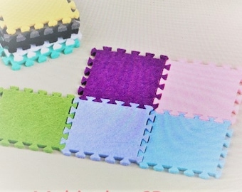 Puede incluir: Un conjunto de seis baldosas de suelo de espuma entrelazadas de colores. Las baldosas son en tonos de verde, morado, rosa y azul. Las baldosas están diseñadas para unirse entre sí para crear un área de juego más grande.