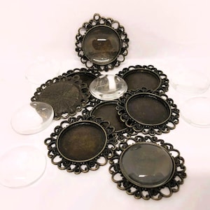 May include: A collection of antique bronze pendant trays and clear glass cabochons. The trays have decorative, scalloped edges. The cabochons are oval and round. Suitable for jewellery making and crafts. The trays are in various sizes.