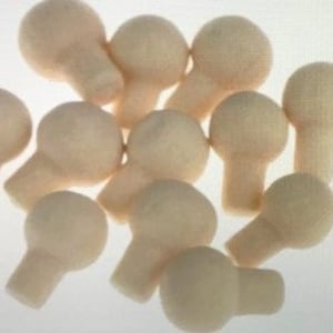 Puede incluir: Un grupo de 12 pomos de madera sin terminar con una parte superior redonda y un tallo corto. Los pomos tienen un diámetro aproximado de 2,5 cm.