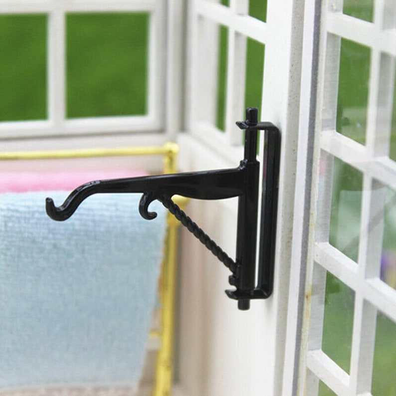 May include: Black metal wall-mounted shelf bracket with a decorative scroll design. The bracket has a curved arm with two hooks at the end.
