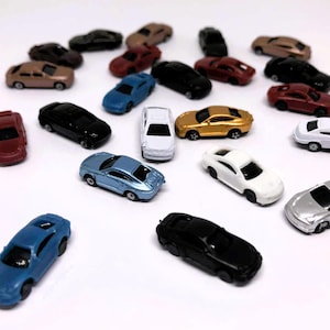 Könnte beinhalten: Eine Sammlung von Miniatur-Spielzeugautos in verschiedenen Farben, darunter Rot, Schwarz, Blau, Weiß und Gold. Die Autos sind auf einer weißen Oberfläche angeordnet und präsentieren ihre unterschiedlichen Designs und Stile. Das Bild zeigt eine vielfältige Auswahl an Spielzeugfahrzeugen.