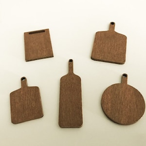 Puede incluir: Cinco tablas de cortar de madera en varias formas y tamaños. Las tablas son todas de color marrón oscuro y tienen una veta de madera natural.