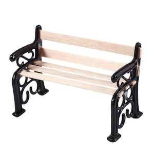 Könnte beinhalten: Miniatur-Parkbank mit schwarzem Metallrahmen und hellen Holzlatten. Die Bank hat dekorative Schnörkel an den Armlehnen und Beinen und ist für Puppenhäuser oder Miniaturszenen konzipiert.