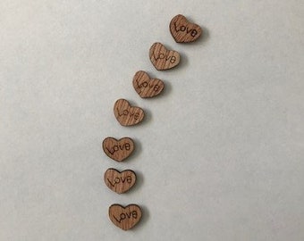 May include: Eight wooden heart-shaped ornaments with the word "Love" inscribed on each. The hearts are arranged in a vertical line, with the top heart at the top of the image and the bottom heart at the bottom of the image.