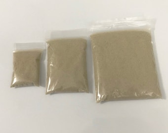 May include: Three clear plastic bags filled with different amounts of beige sand.