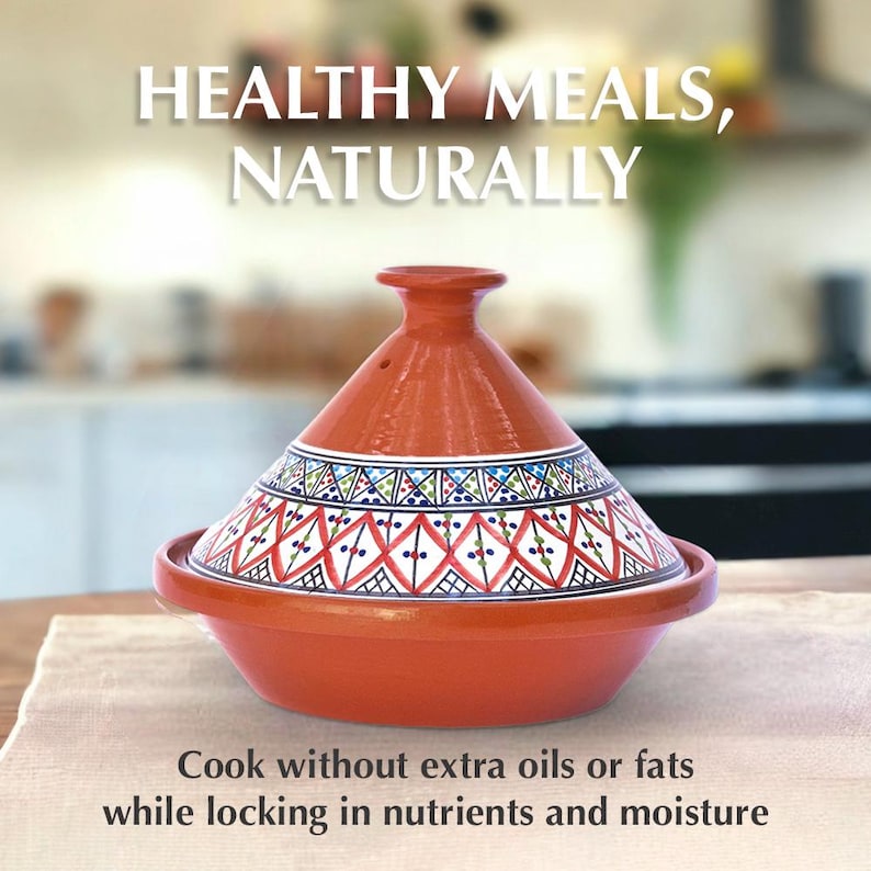 May include: A red clay tagine with a white and blue geometric pattern. The tagine is a traditional Moroccan cooking pot used for slow cooking. "HEALTHY MEALS, NATURALLY" is written in white text above the tagine. The text below the tagine reads "Cook without extra oils or fats while locking in nutrients and moisture."