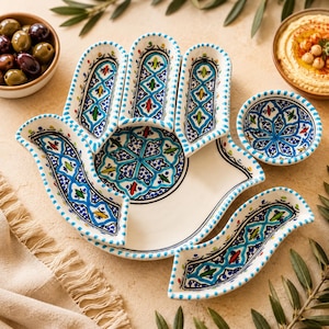 May include: A white ceramic serving platter and bowls with a hand-shaped design. The platter and bowls feature intricate blue, green, and red patterns. The set is ideal for serving appetizers or snacks.