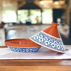 May include: A traditional Moroccan tagine cooking pot with a lid. The pot is made of terracotta and features a blue and white geometric pattern. The lid is a cone shape and has a similar pattern.