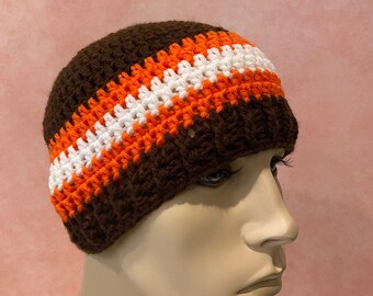 May include: A brown crocheted beanie with white and orange stripes.