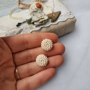 May include: A pair of white pearl stud earrings. The earrings are round and have a cluster of small pearls.