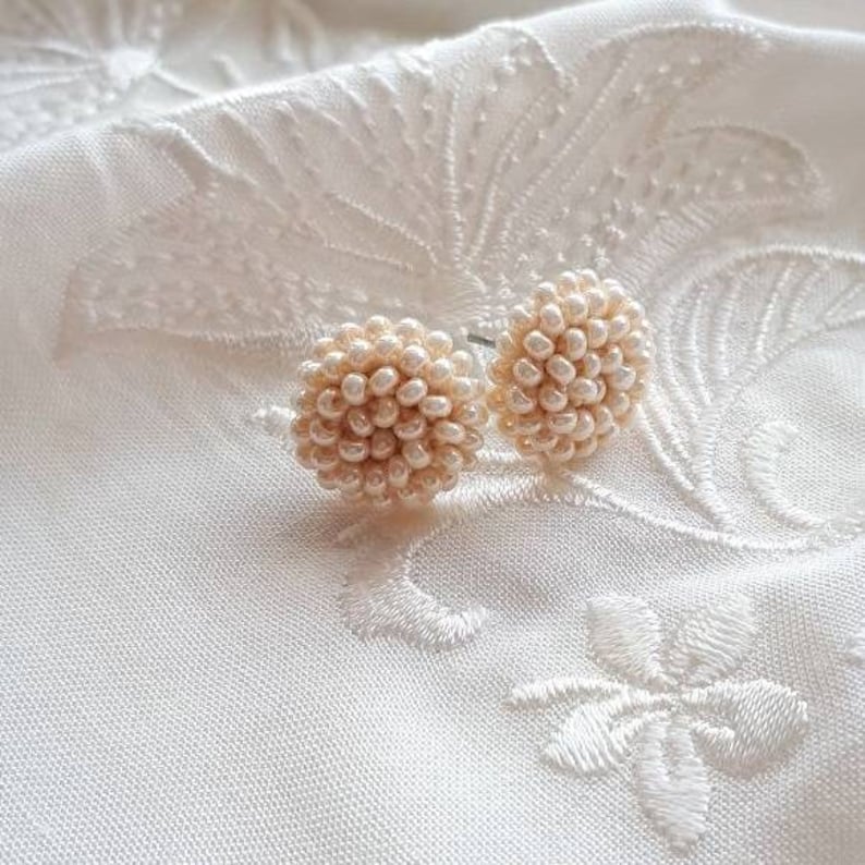 May include: A pair of pearl bead earrings in a cream color. The earrings are round and have a cluster of small pearls.