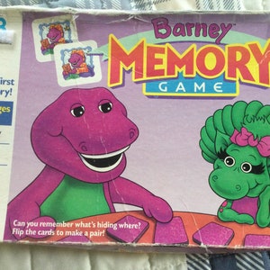 May include: A purple dinosaur named Barney and a green dinosaur with a pink bow are on the box of a Barney Memory Game. The box says "Your First Memory!" and "For Ages 3 to 6".