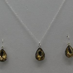 May include: A silver necklace and earrings set with teardrop-shaped amber-colored crystals.