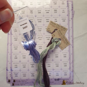 Peut inclure: Gros plan sur des bobines de fil à broder avec des étiquettes de couleur et des numéros. Le fil est dans des tons de violet, vert et marron. Les étiquettes indiquent "Weeks Dye Works" et "Periwinkle 2337".