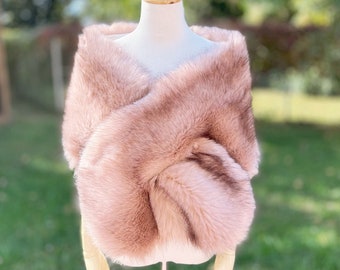 May include: A blush pink faux fur shawl draped over a mannequin. The shawl is soft and fluffy, and it would be perfect for a special occasion.