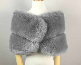 May include: A gray faux fur shawl with a simple design. The shawl is displayed on a mannequin.