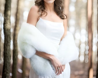 Puede incluir: Una mujer con un vestido blanco y una estola de piel blanca de pie en un bosque. Ella está sonriendo y mirando a la cámara.