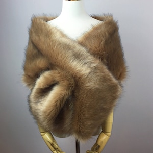 May include: A brown faux fur shawl draped over a mannequin. The shawl is soft and fluffy, and it would be perfect for a wedding or other special occasion.