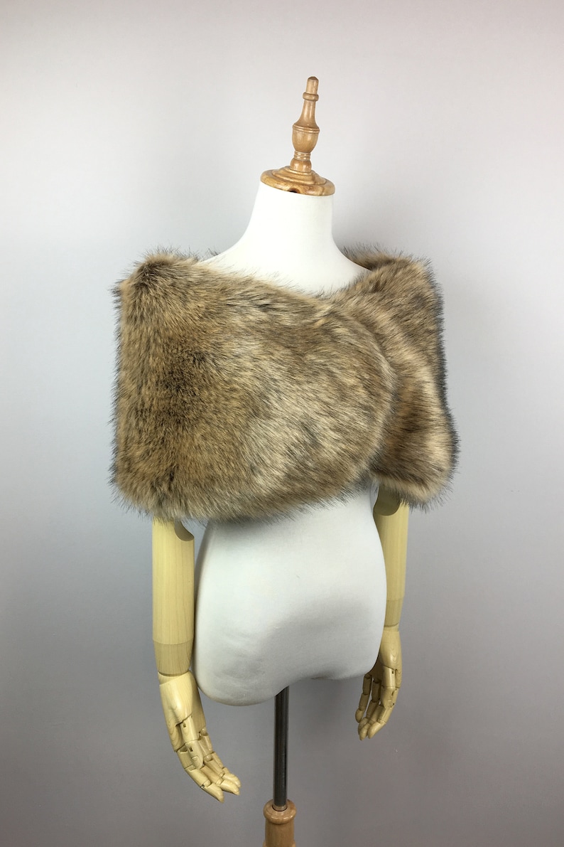 May include: A brown faux fur shawl with a soft, fluffy texture. The shawl is draped over a white mannequin.
