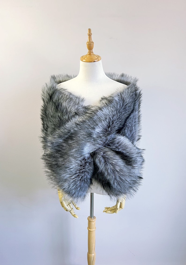 May include: A gray faux fur shawl draped over a mannequin. The shawl is soft and fluffy, and it would be perfect for a special occasion.