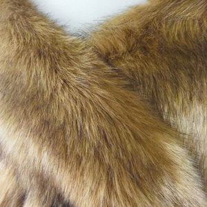 May include: A brown faux fur shawl with a soft, fluffy texture. The shawl is folded in half and draped over a mannequin's shoulders.