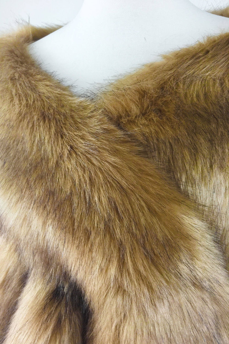 May include: A brown faux fur shawl with a soft, fluffy texture. The shawl is folded in half and draped over a mannequin's shoulders.