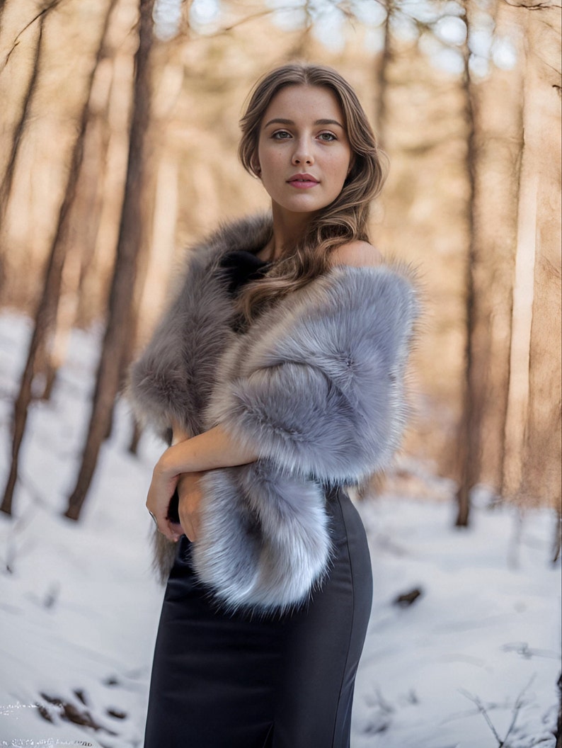May include: A woman wearing a gray faux fur shawl over a black dress, standing in a snowy forest.