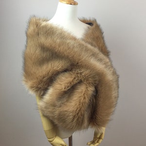 May include: A brown faux fur shawl draped over a mannequin. The shawl is soft and fluffy, and it would be perfect for a special occasion.