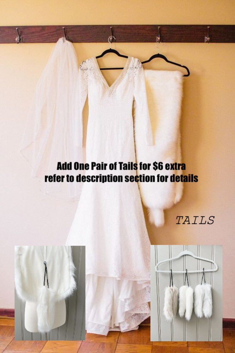 May include: A white wedding dress with lace detailing hangs on a hanger with a white fur shawl and a white veil. The dress has a long train and a fitted bodice. The image also shows a close-up of a white fur tail and a set of five white fur tails hanging on a hanger. The text "Add One Pair of Tails for $6 extra refer to description section for details" and "TAILS" is visible in the image.